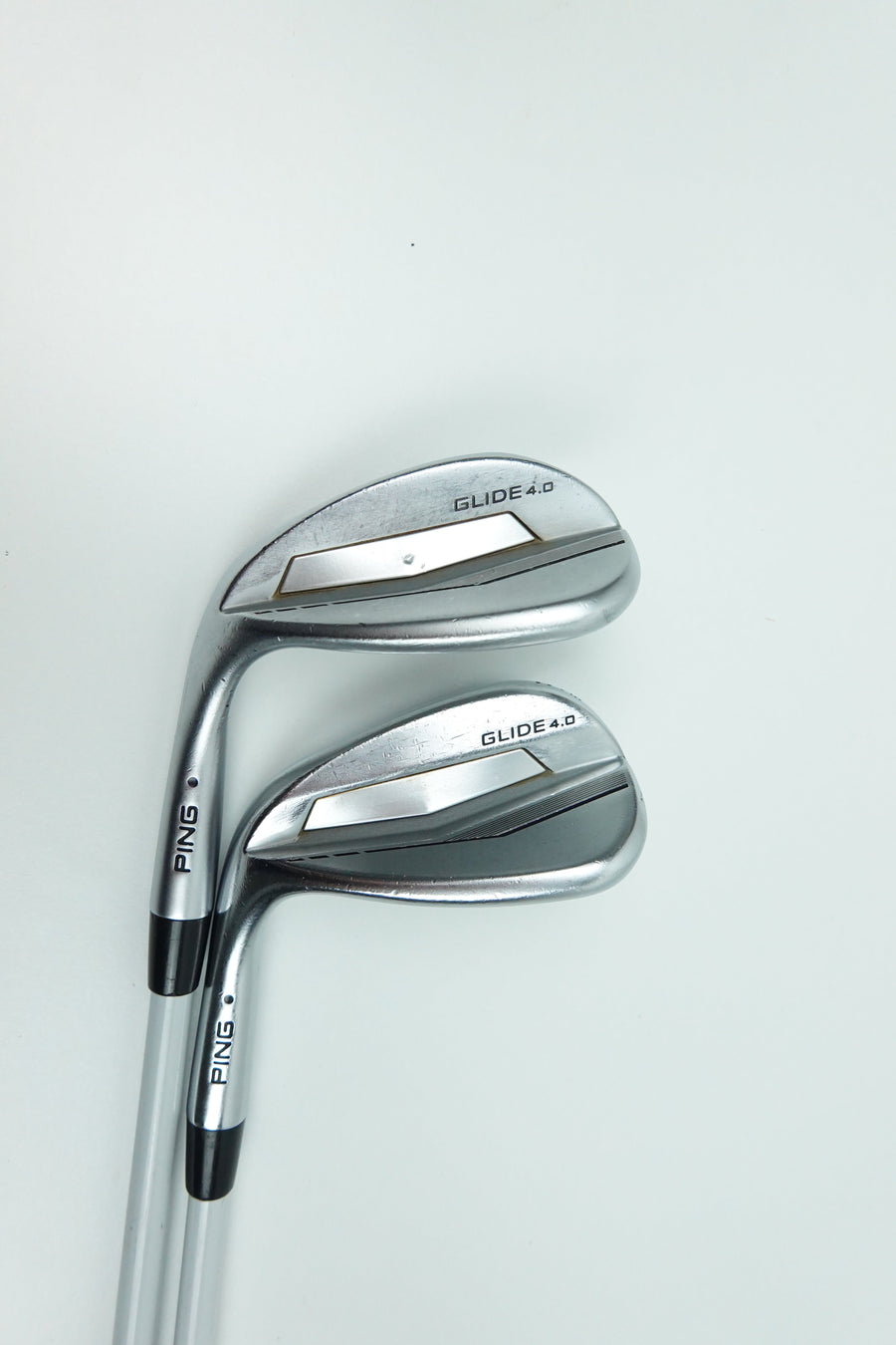 Two PING golf wedges with metallic silver and black clubs, positioned diagonally on a clean white background.